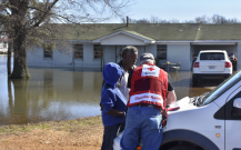 Paul Strickland and his son Paul Strickland, Jr. share their ordeal and complete paperwork with Red Cross caseworker Mike Peterson in front of his Robinsonville, Mississippi, home now surrounded by floodwaters.