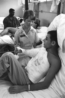 June 1968. Qui Nhon, South Vietnam. PROBLEMS HANDLED HERE . If a patient at the 67th Evacuation Hospital in Qui Nhon has a problem, he calls it to the attention of Red Cross hospital worker Evelyn Hardison. Here she is consulted by SP4 Irwin Cohen, who comes from San Francisco. Red Cross staffers provide sick and wounded servicemen at the 67th with non-medical personal attention and casework services, such as arranging emergency communications between a wounded man and his worried family at home. Photo by Mark Stevens/American Red Cross